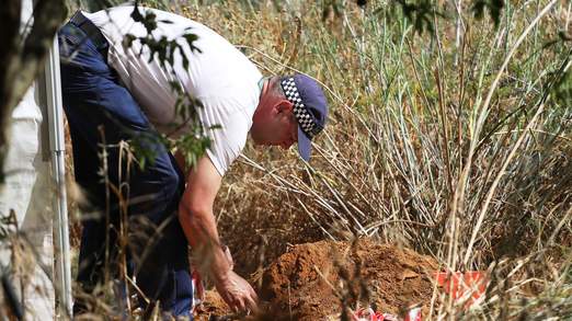 A police officer checks soil samples